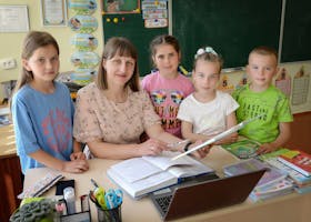 A teacher with four students in a classroom encouraging education and learning.