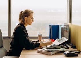 Dedicated woman using laptop and calculator in modern office setting.